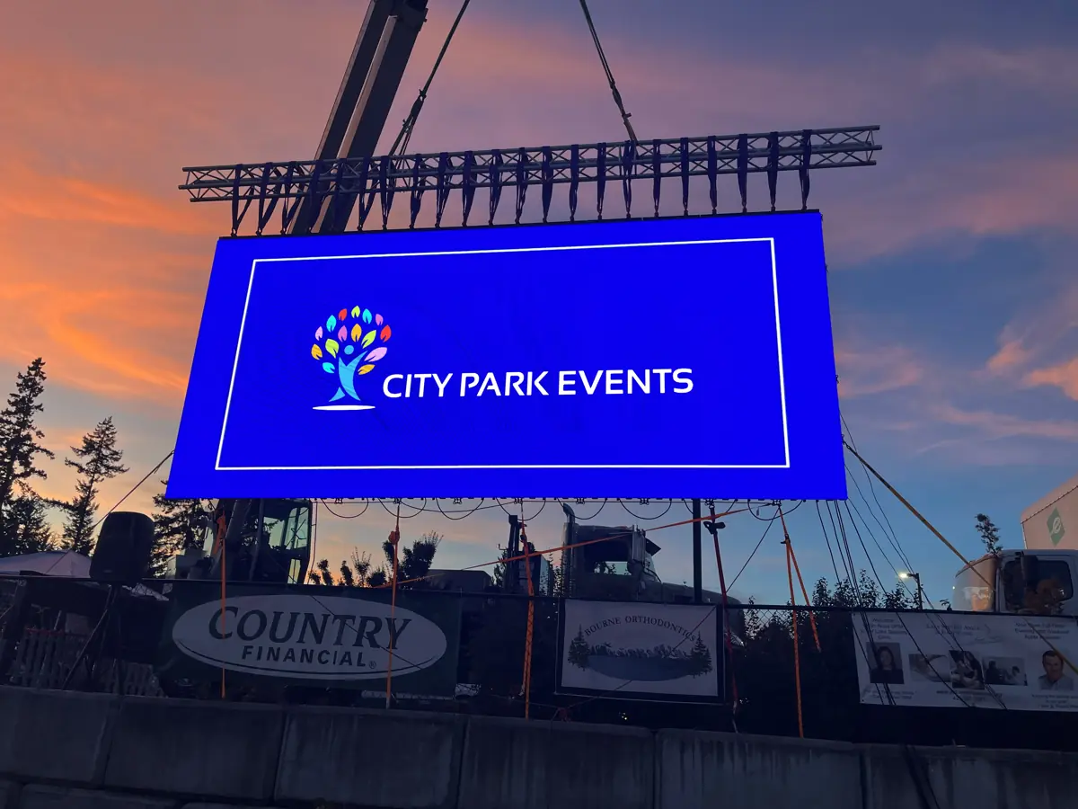 A City Park Events video wall hanging from a crane at a festival in Lake Stevens at sunset